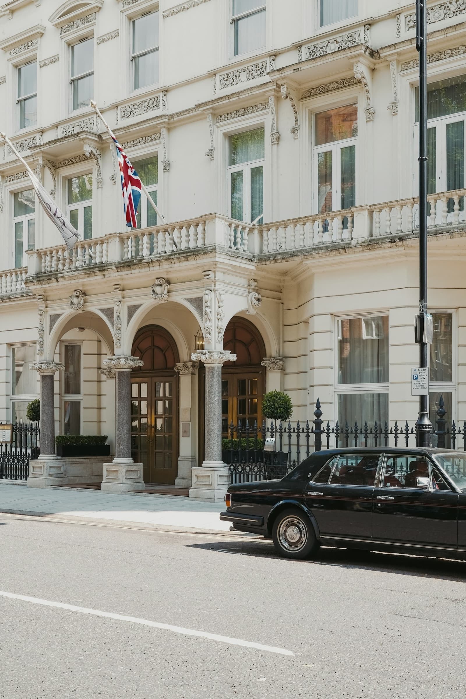 A white stone hotel front in London, a vintage car parked outside