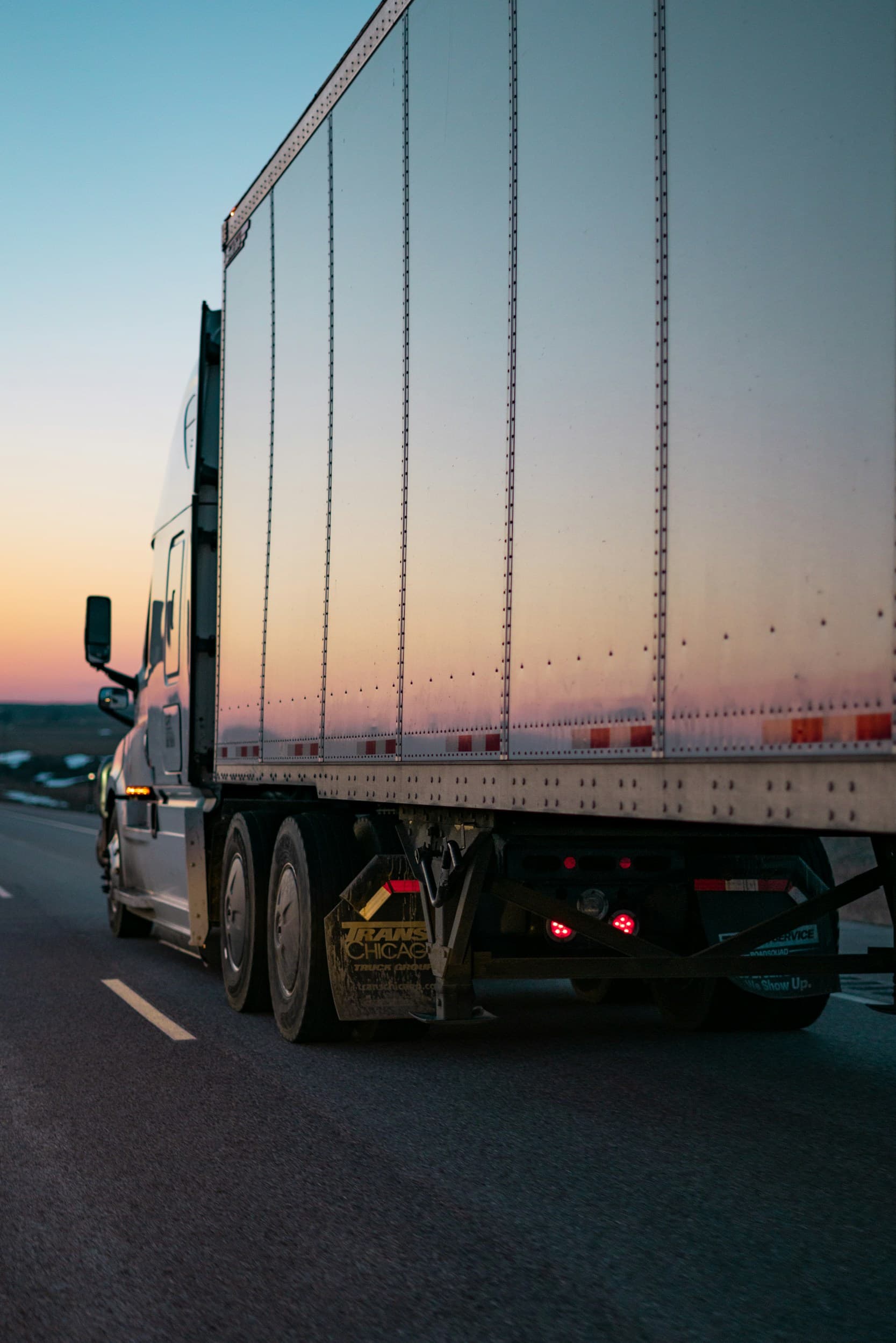An articulated lorry on a motorway at dusk