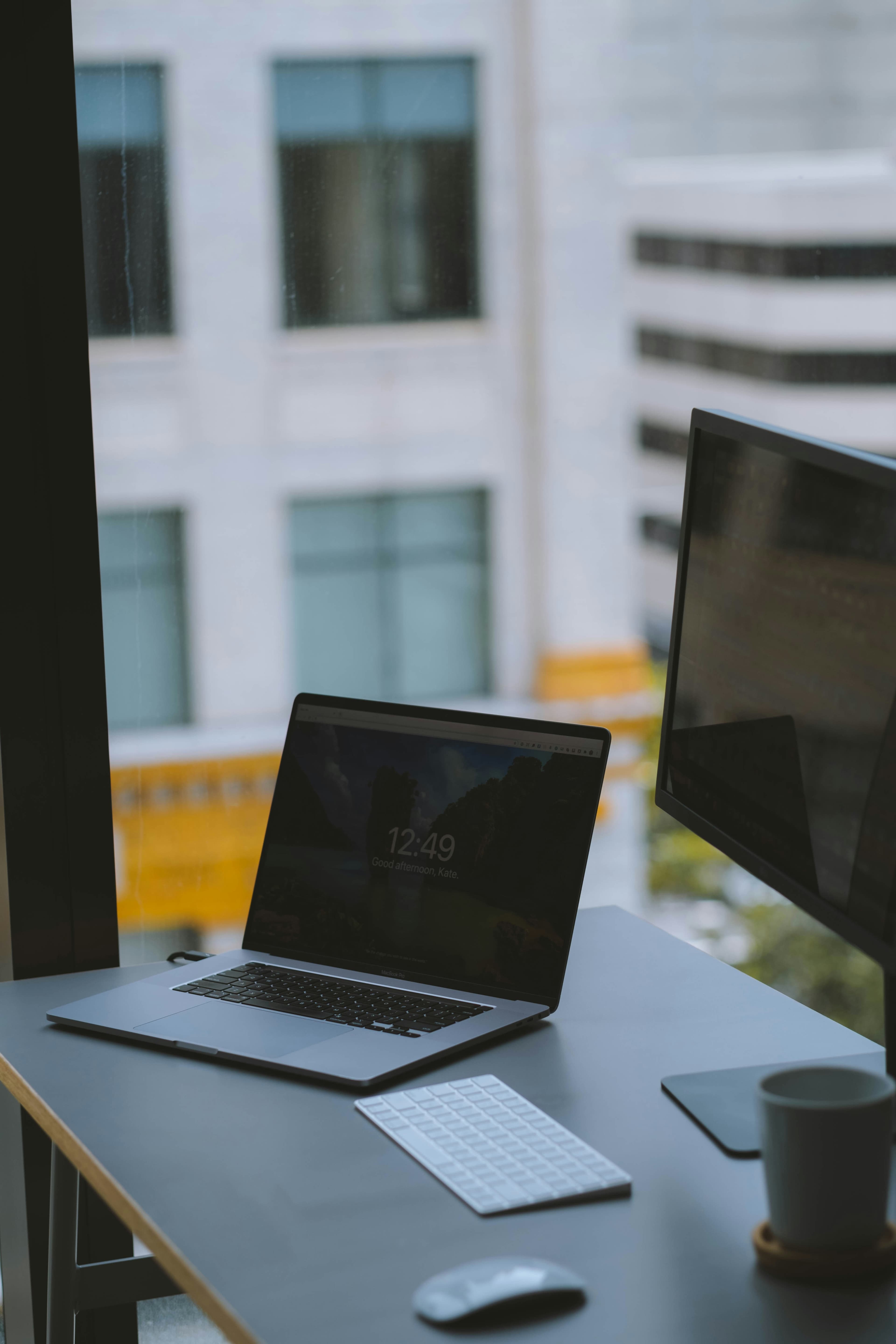 A laptop open on a desk by an office window