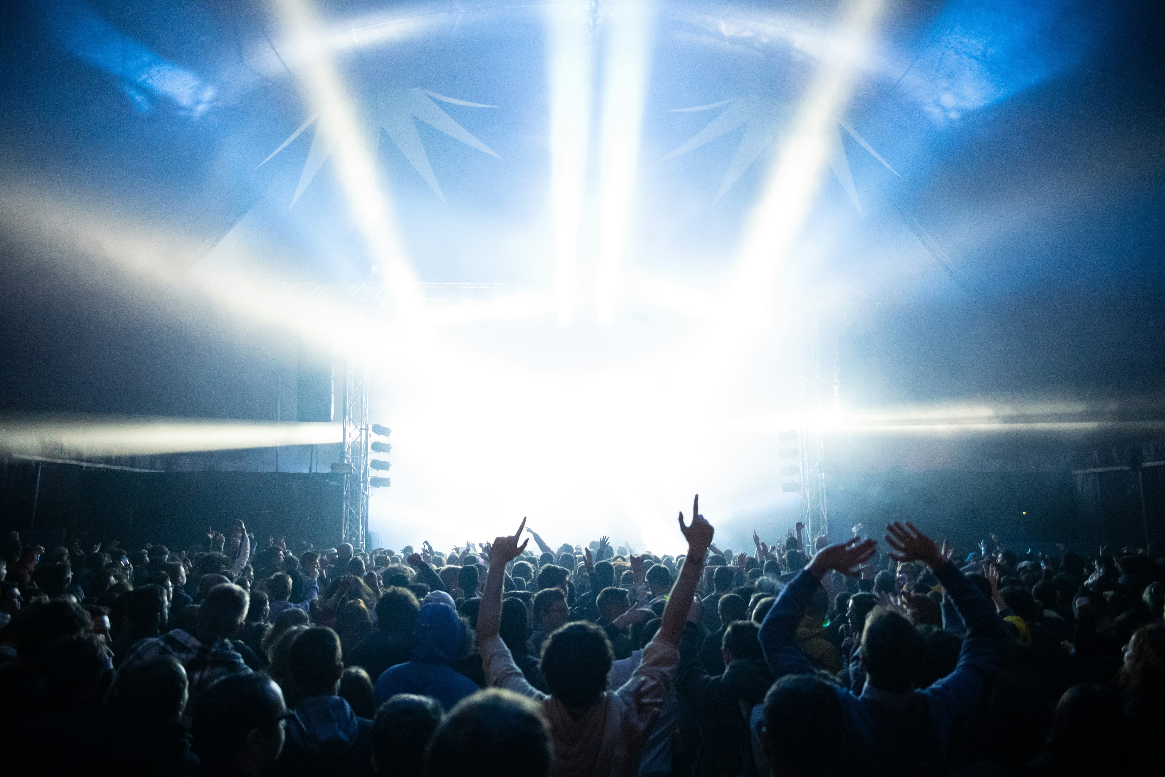 A crowd with raised hands under bright stage lights