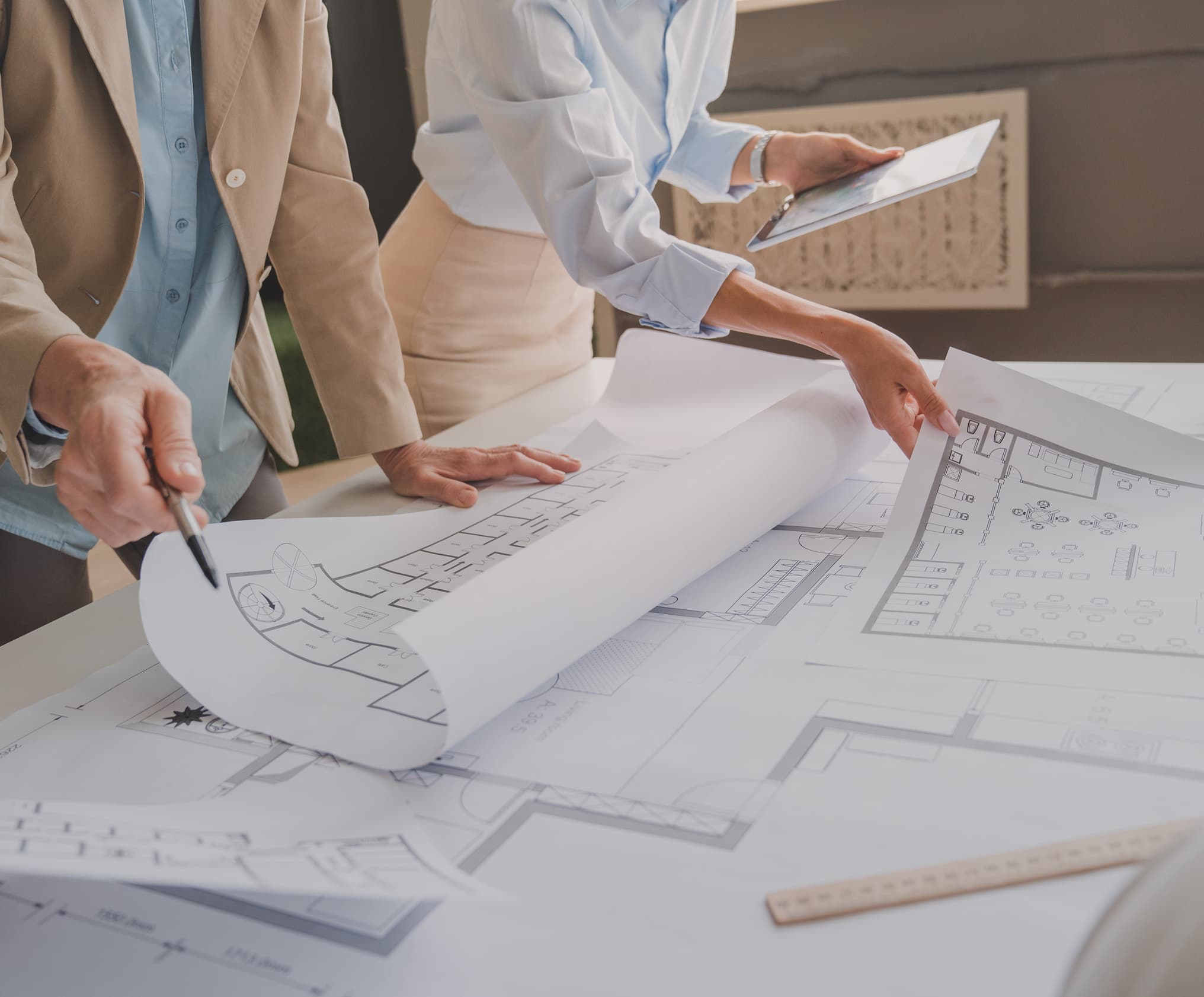 Two colleagues pointing out details on a set of architectural drawings