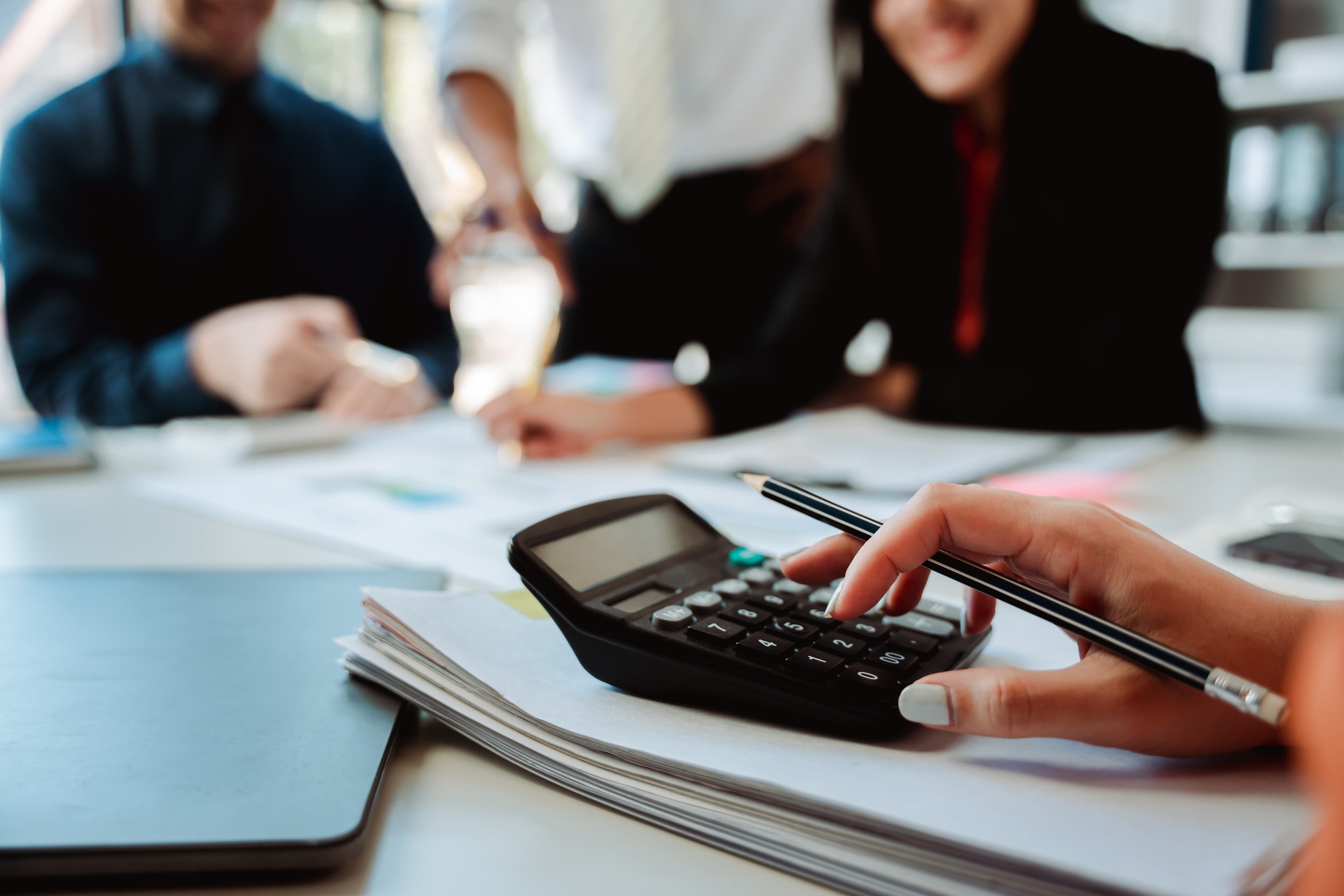 A calculator and pen on a desk of financial papers
