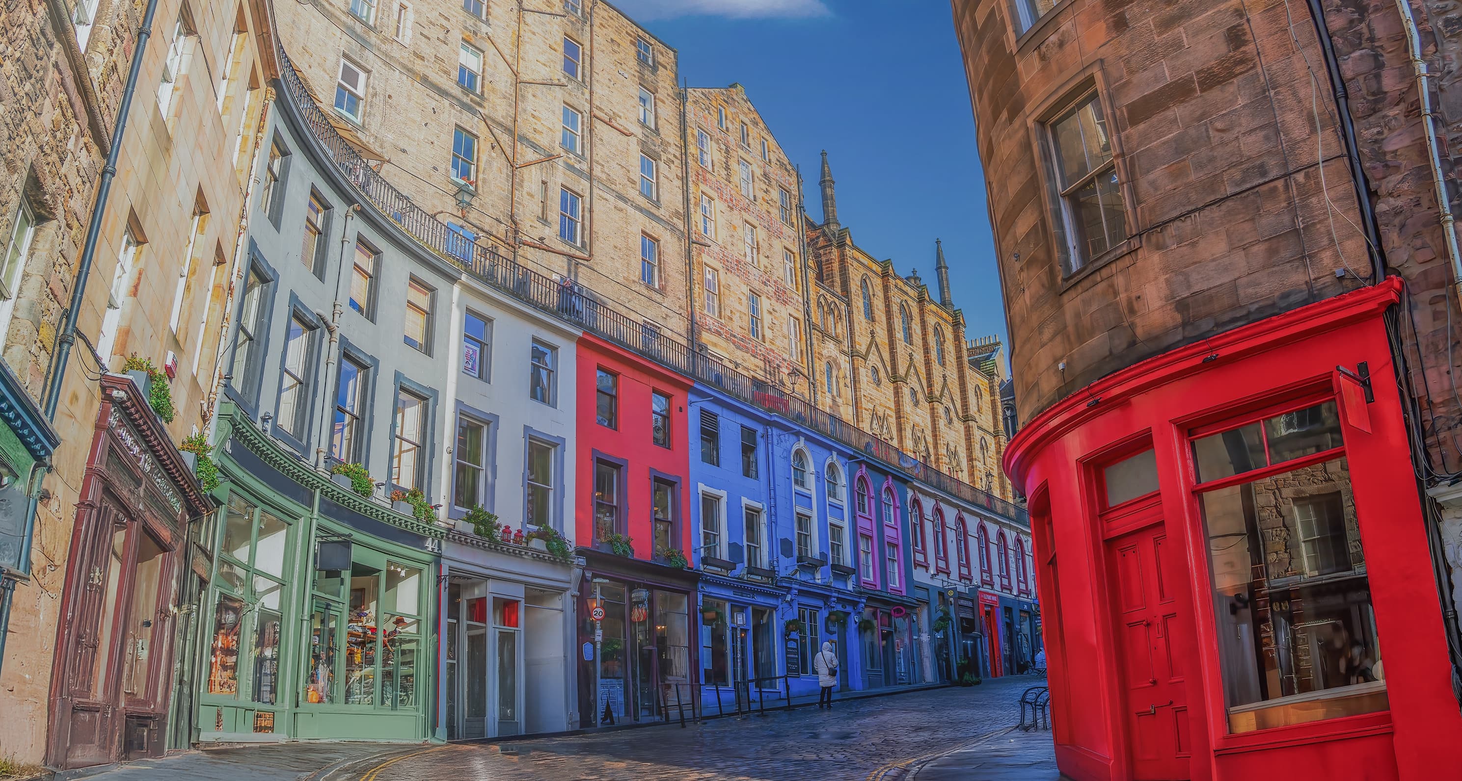 A curving street of brightly painted shopfronts with flats above