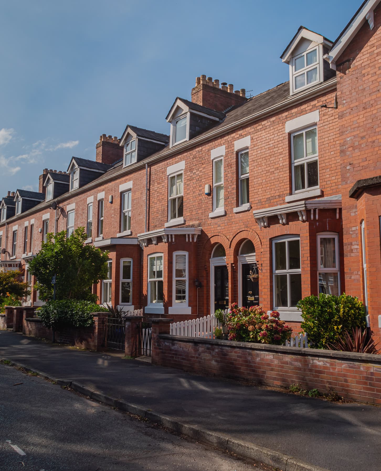 A red-brick terrace of houses along a quiet Manchester street