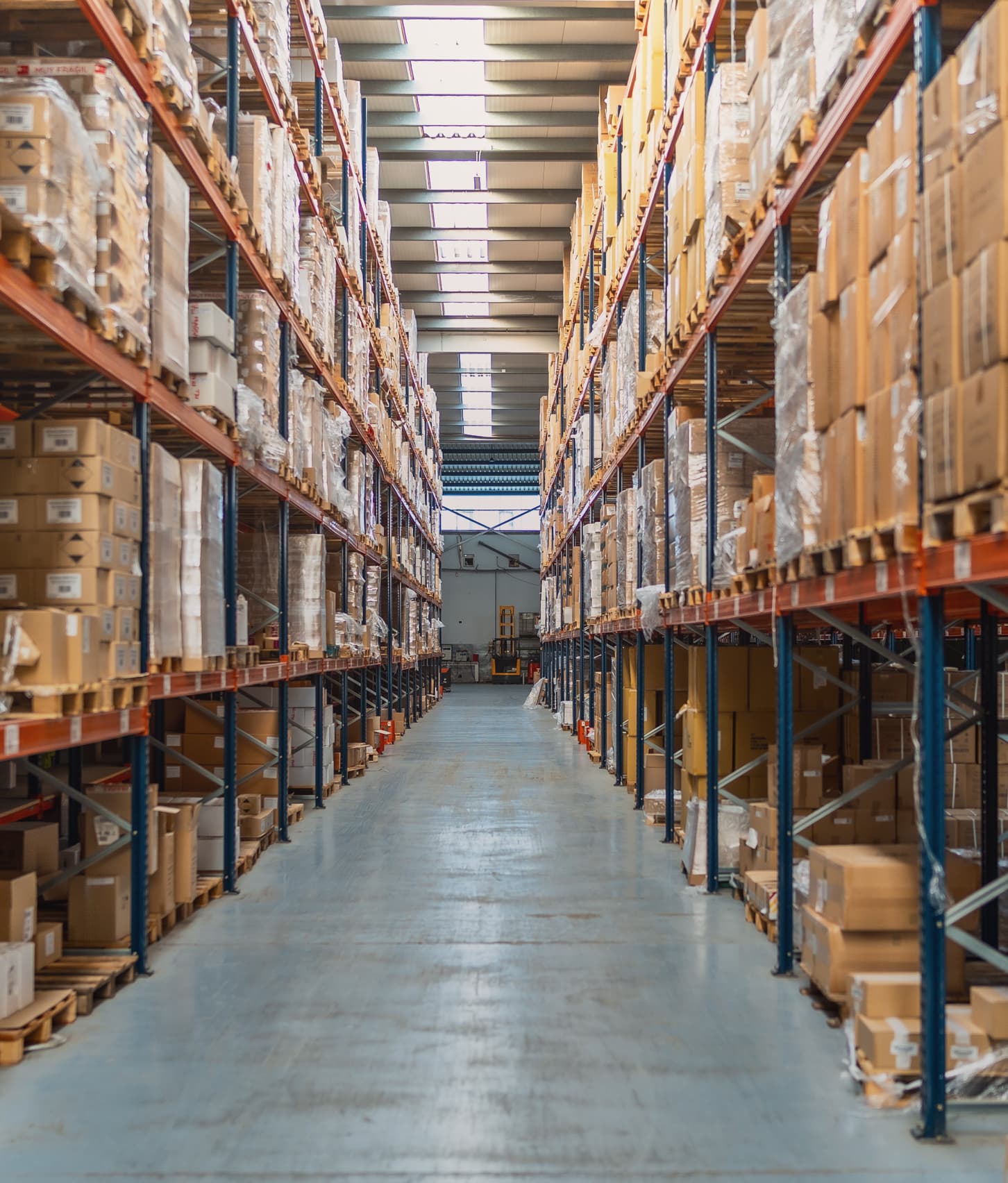 A long warehouse aisle between tall racks of boxed stock